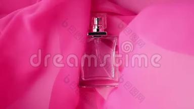 平面瓶与青色香水或精油是在粉红色的布上。 粉红色的织物在周围飘来飘去，在周围荡来荡去